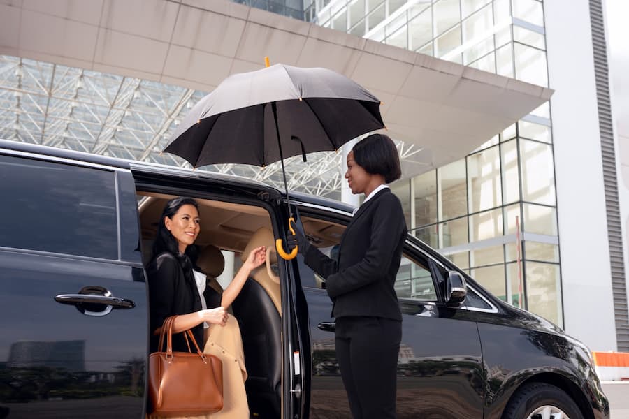 A woman with an umbrella is entering a car and telling How to Book a Transfer from Airport to Hotel